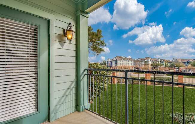 A balcony with a green door and a black railing.