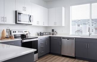 2 BR Apartments in Oregon City OR - Timberview Apartments and Townhomes - Bright Modern Kitchen with a Large Window, Stainless Steel Appliances, White Quartz Countertops, and White and Dark Grey Cabinetry