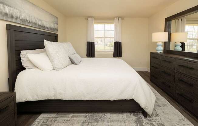 A bedroom with a large bed, a dresser, and a mirror.