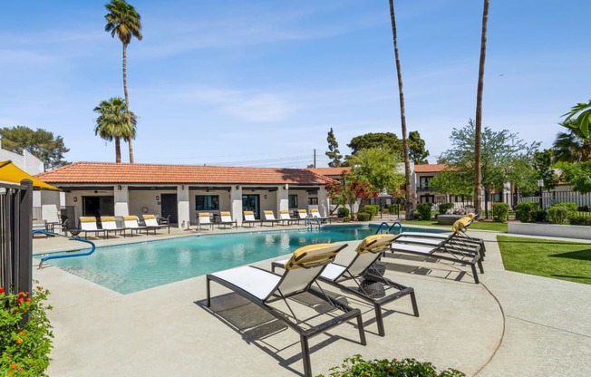 a swimming pool with chaise lounge chairs and a building in the background