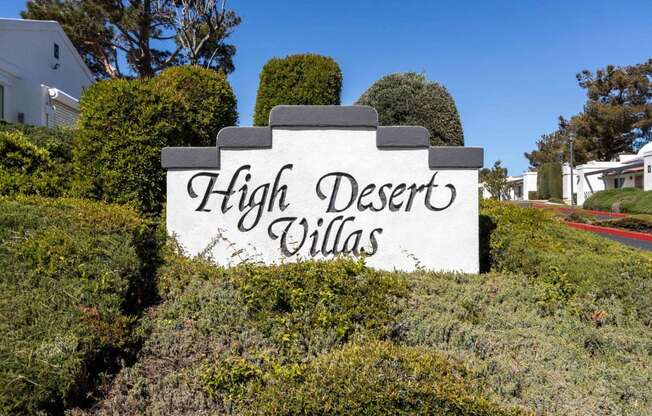 a sign that says high desert villas in front of bushes