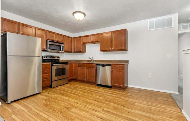 A kitchen with wooden cabinets and a stainless steel refrigerator.
