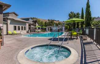 our resort style hot tub is surrounded by patio furniture and a pool