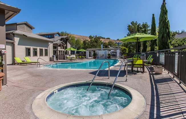 our resort style hot tub is surrounded by patio furniture and a pool