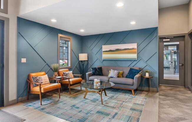 A living room with a blue wall and a painting of a beach scene.