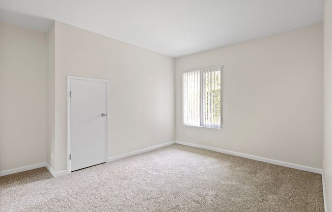 a bedroom with white walls and carpet