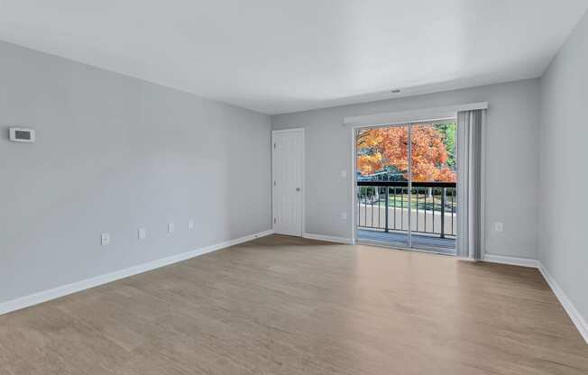 the living room of an empty house with a door to a balcony