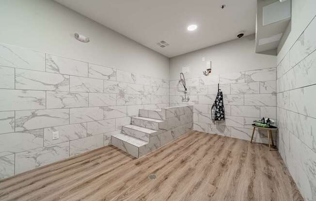 A bathroom with marble tiles on the walls and wooden flooring.