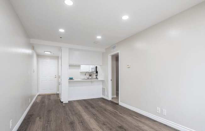a living room and kitchen with white walls and wood flooring at Huntington Terrace North Senior, Huntington Beach, CA 92648