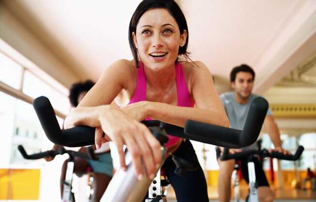 a woman cycling on an exercise bike at a gym
