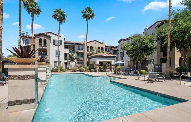 A swimming pool surrounded by palm trees and apartment buildings.