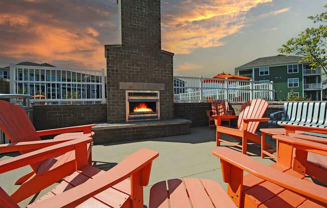 A fireplace is surrounded by red chairs and tables.