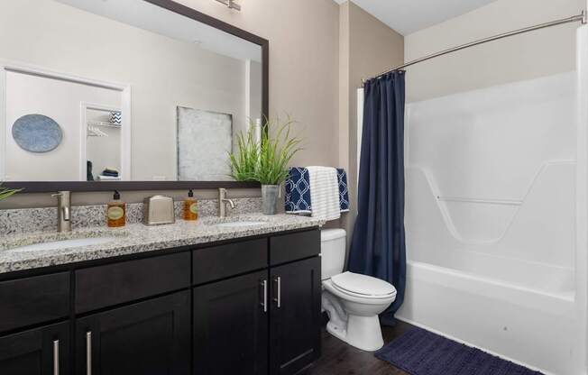 A bathroom with a white tub, sink, and dark wood cabinets.