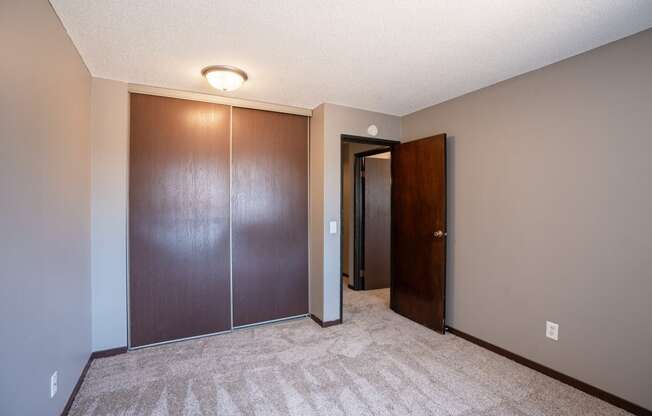 a bedroom with a closet and a door to a hallway. Roseville, MN Rosedale Estates Apartments