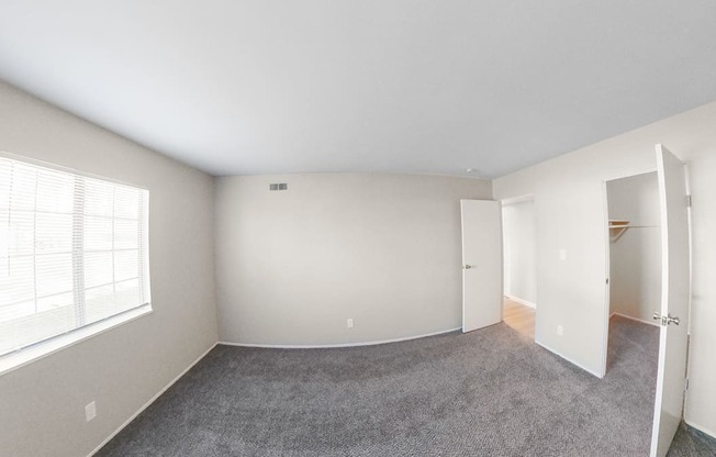 an empty bedroom with a large window and a closet