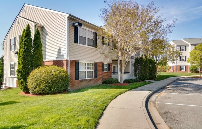 A residential building with a white and beige exterior and a green lawn in front.