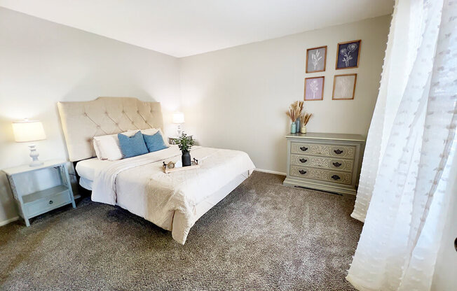 a bedroom with a bed and a window with white curtains