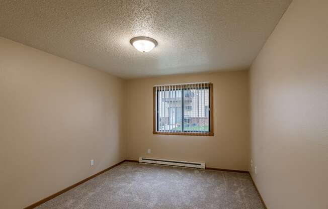 Grand Forks, ND Richfield Apartments. A bedroom with carpeted floors and a window.