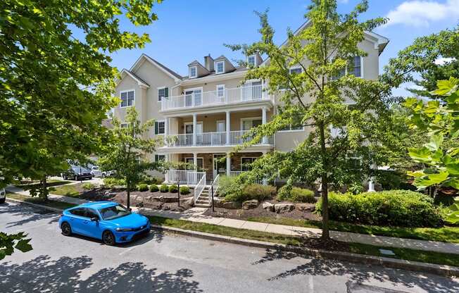 A blue car is parked on the street in front of a white building.