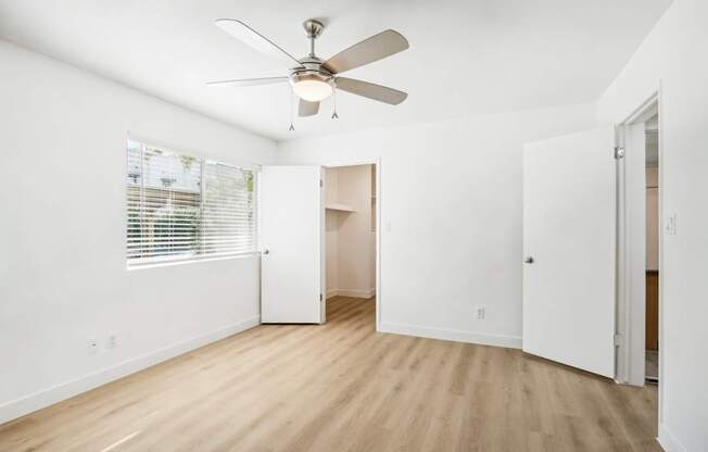 A room with a ceiling fan and a window with blinds.