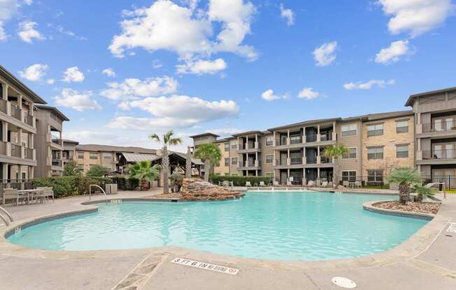 A large swimming pool in front of apartment buildings.
