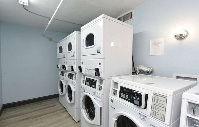 A stack of white front load washing machines in a laundromat.