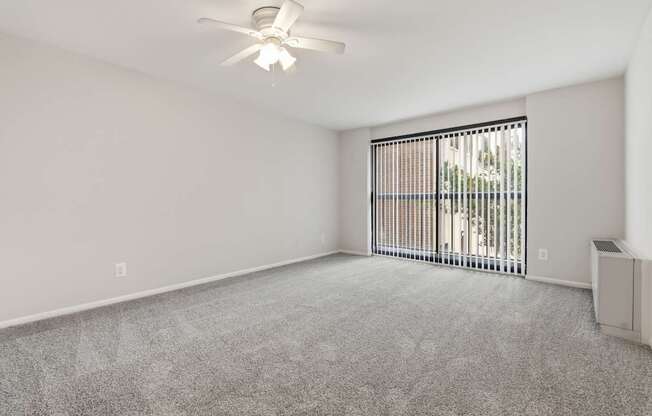 A room with a ceiling fan and a window with blinds.