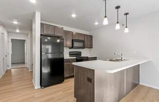 A kitchen with a black fridge, microwave, and stove top oven.