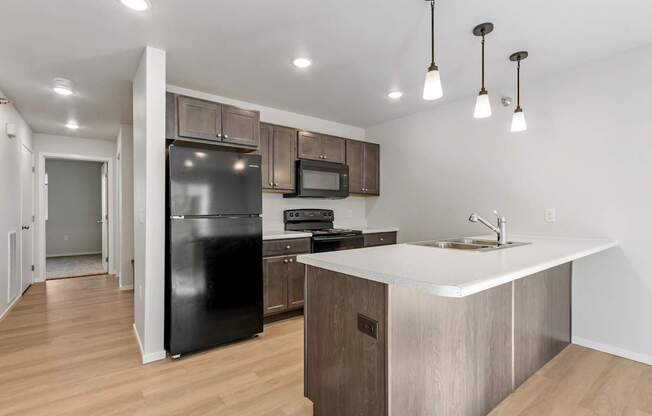 A kitchen with a black fridge, microwave, and stove top oven.