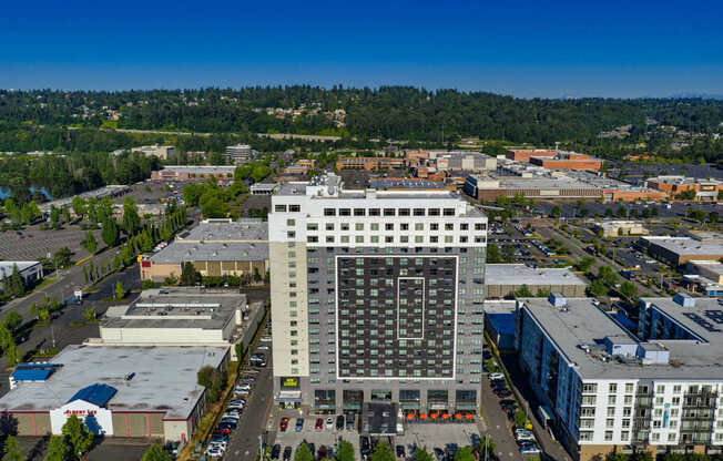 A large building with a lot of windows is in the middle of a parking lot.
