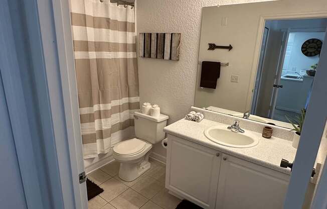A bathroom with a toilet, sink, and shower curtain.