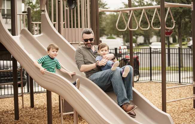Parent playing with his children on the playground at Lake Nona Water Mark