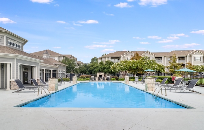 A large swimming pool surrounded by lounge chairs and umbrellas in a residential area, Plantation Crossing, Lafayette, LA, 70508