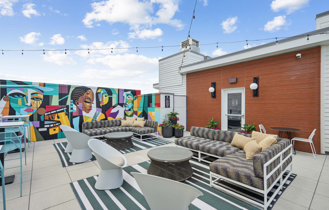 a patio with couches and chairs and a mural on the wall