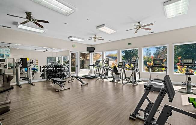 a gym with cardio equipment and windows