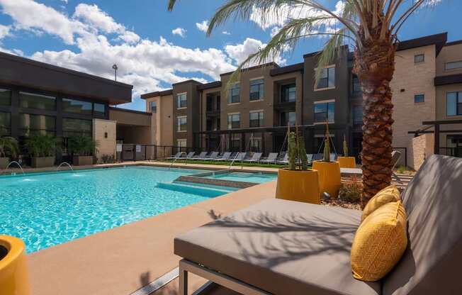 A pool area with a palm tree and a couch.