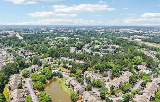 A bird's eye view of a residential area with a pond in the middle.
