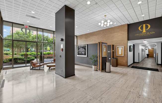 The interior of a hotel lobby with a large glass wall and a wooden floor.