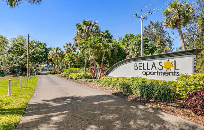 A street view of Bellas Apartments with a sign and a road.