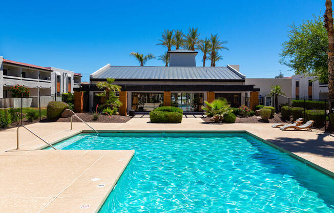 a swimming pool in front of a building with palm trees