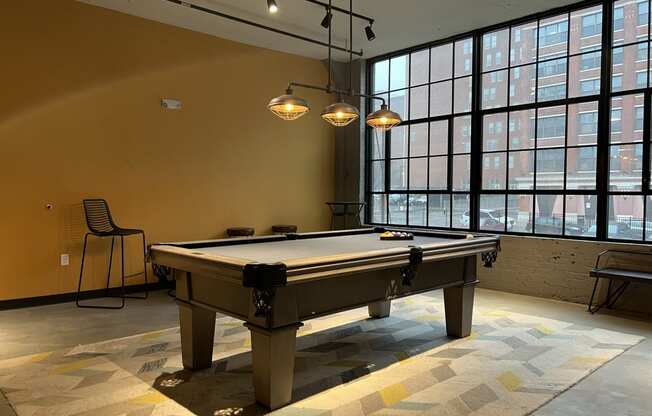 a pool table sits in the middle of a room with large windows and a yellow wall