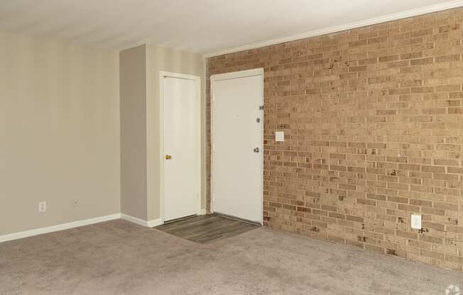 an empty living room with a brick wall and two doors