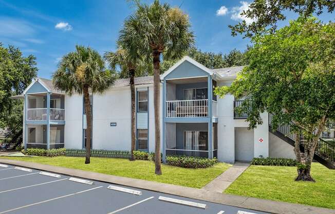 a white apartment building with palm trees in front of it at Aqua Bay Apartments in Naples, FL 34116