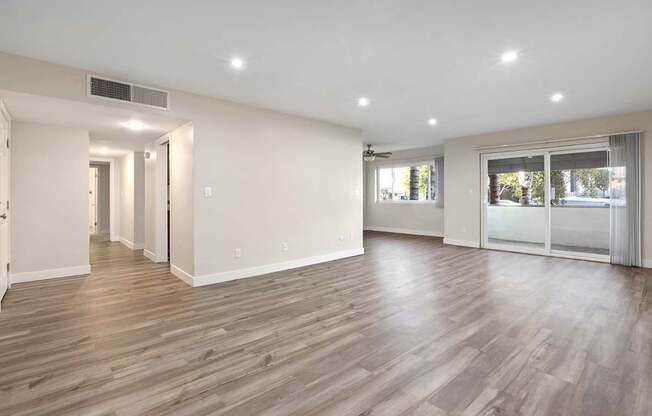 Spacious room with wooden flooring and white walls.