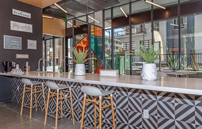 A modern bar with a white counter and wooden stools.