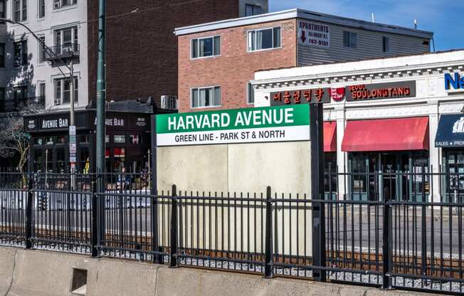 a sign in front of a metal fence identifying the Harvard Avenue MBTA Green Line stop, Allston MA