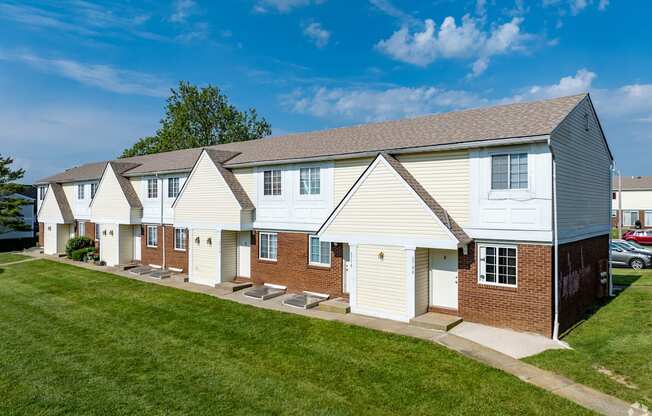 a row of white houses with a green lawn and a blue sky