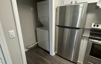 an empty kitchen with a stainless steel refrigerator and washer and dryer