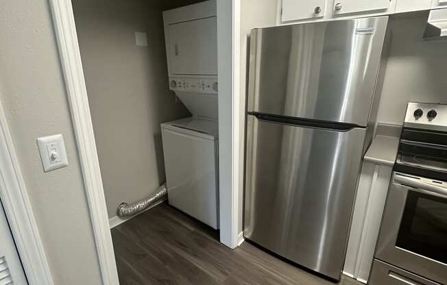 an empty kitchen with a stainless steel refrigerator and washer and dryer