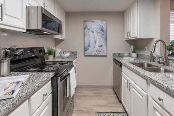 galley kitchen with granite countertops , stainless steel appliances, and modern fixtures at Preserve at Cedar River Apartments, Jacksonville, Florida
